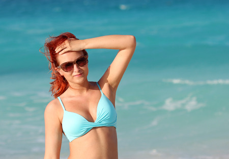 The redhead young woman standing in the ocean waterの写真素材