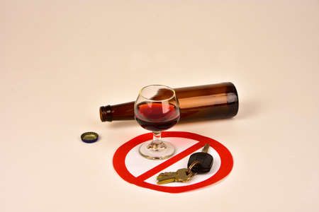 Glass of wine with empty beer bottle and ignition key in prohibition circle, symbols of driving drunk.の写真素材