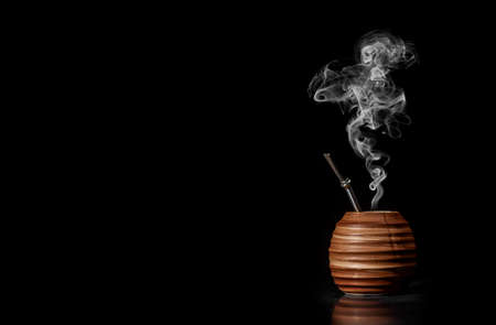 Beautiful yerba pot. Clay Matero. Side view on black background. Space for text