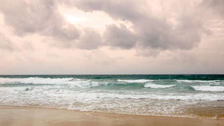 Sunset on Karon beach. Heavy clouds over the sea. The surf pounds the shore. Phuket, Thailandの写真素材