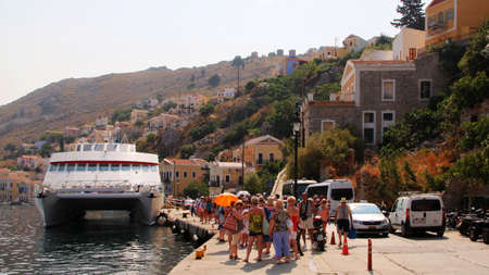 Travelers of King Saron passenger catamaran come ashore in the port of Symi, Symi island, Greece