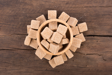 Brown cane sugar cubes on wooden background. top viewの写真素材