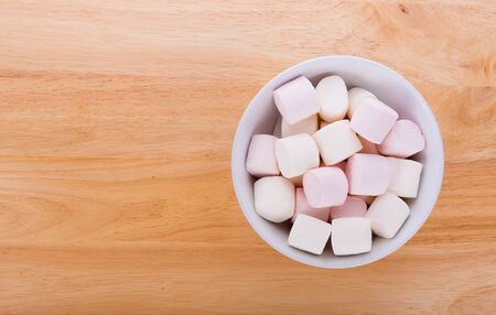 Marshmallows in a bowl on wooden backgroundの写真素材