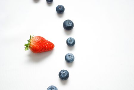 Red strawberry pointing to blueberriesの写真素材