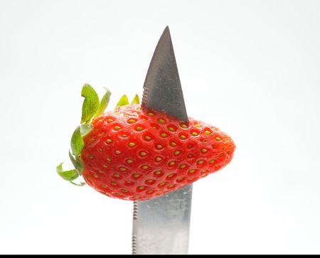 Knife penetrating red strawberryの写真素材