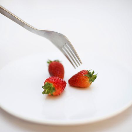 Strawberries and silver fork on tableの写真素材