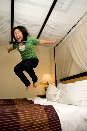 Asian girl jumping on bedの写真素材