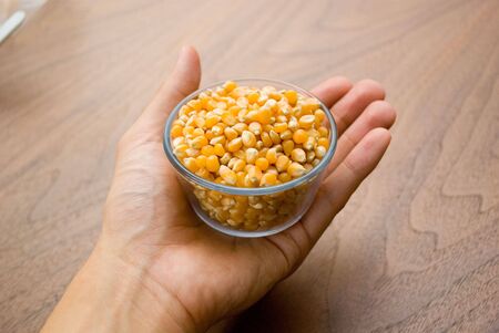 Hand holding a cup of corn kernel