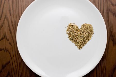 Cumin seeds in love shape on white plateの写真素材