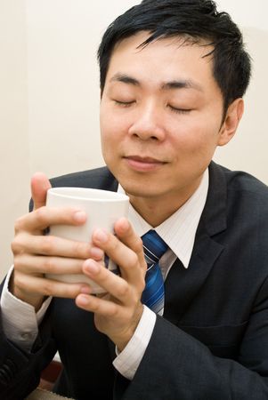 Asian business guy enjoying a mug of coffeeの写真素材