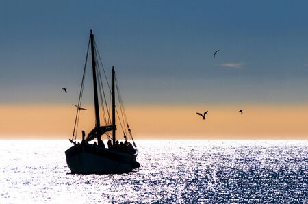 GIRONA, SPAIN: JANUARY 30, 2010. Sailing boat sailing with people surrounded by seagulls at Costa Brava.のeditorial素材