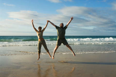 Man and woman jumping in a sunny beachの写真素材