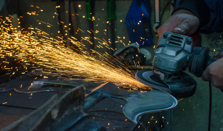 Industrial grinder showers sparks while working with metal.