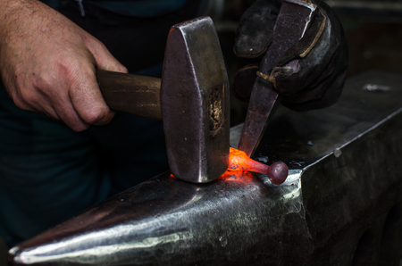 Blacksmith at work, hit with a hammer by a hot metal on the anvil.の写真素材