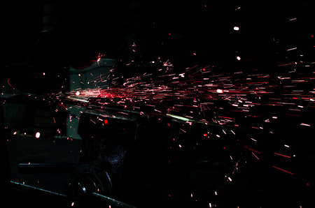 Industrial grinder showers sparks while working with metal.の写真素材
