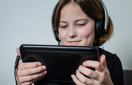 Girl playing with a digitizert on the couch.の写真素材