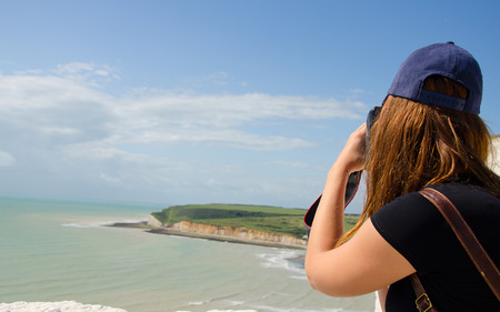 A tourist photographing the English coast with cliffs of seven sisters.