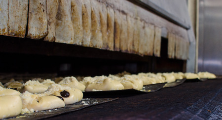 Sweet pastry going to a large oven in a big bakeryの写真素材