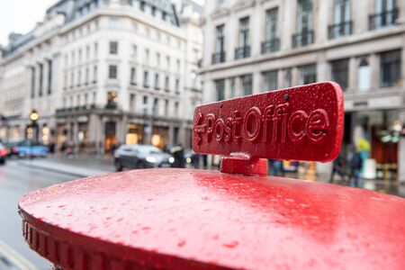 English red mailbox sending a letter in a busy London street.の写真素材