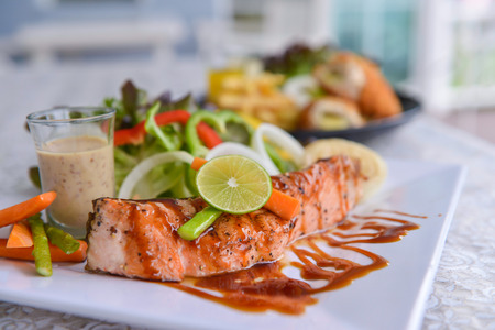 Fried steak from a salmon with a sauce and lemon, ready to the serveの写真素材