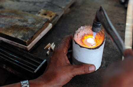 Close up of Jeweler crafting silver bracelet with flame torch.