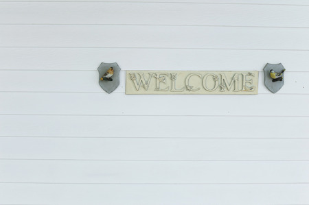 Welcome on woodenboard hanging outside at a white wooden wallの写真素材