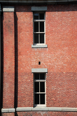 Old red brick building or factory with many small windowsの写真素材