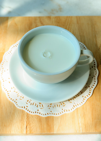 Hot milk in ceramic cup on wooden tableの写真素材