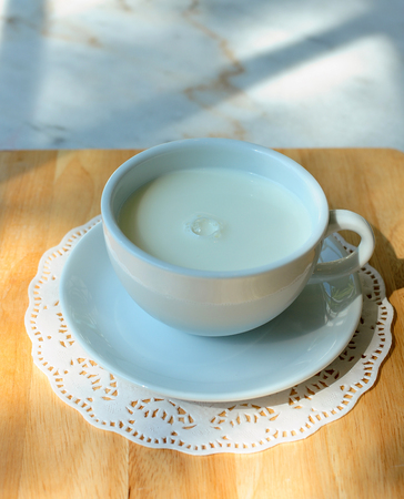 Hot milk in ceramic cup on wooden tableの写真素材