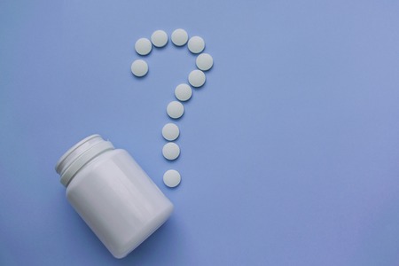Medicines are white, round pills with a core, isolated on a purple background.の写真素材