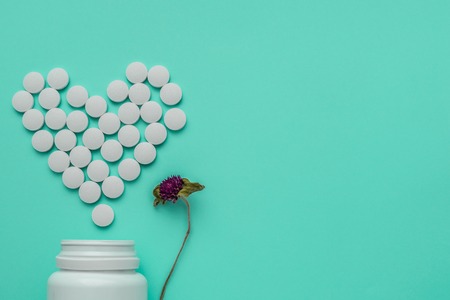 Medicines white, round heart shaped pills isolated on turquoise background.の写真素材
