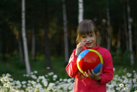 little girl with ball among the daisies            の写真素材