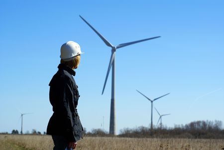 Woman engineer or architect with white safety hat and wind turbines on background