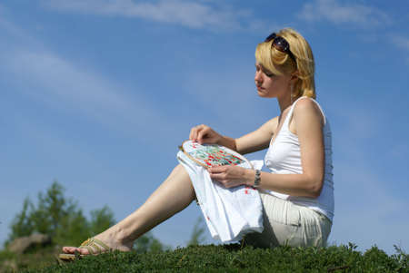 woman cross-stitching in the park with blue sky on background の写真素材