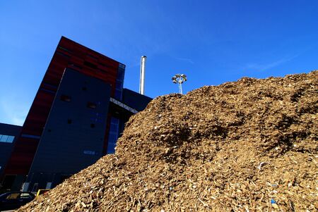bio power plant with storage of wooden fuel against blue sky