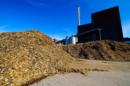 bio power plant with storage of wooden fuel (biomass) against blue skyの写真素材