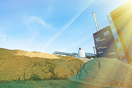 bio power plant with storage of wooden fuel (biomass) against blue skyの写真素材