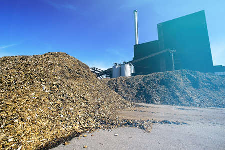 bio power plant with storage of wooden fuel (biomass) against blue sky