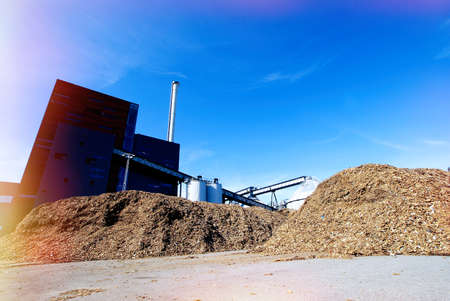 bio power plant with storage of wooden fuel against blue skyの写真素材