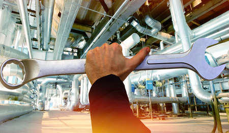 Service Factory concept background. Hand holding a wrench against factory photo