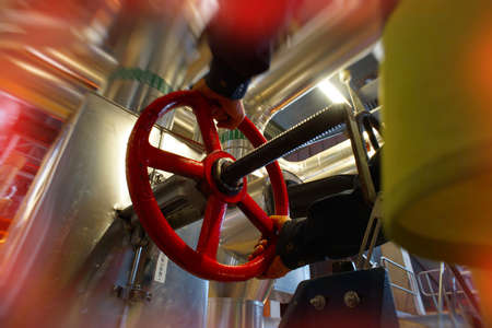 industrial factory worker turning red wheel of valve