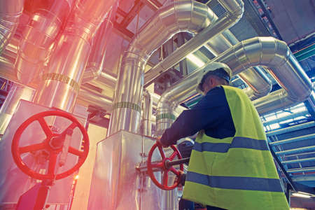 industrial factory worker turning red wheel of valve