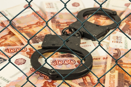 The cuffs on the background of Russian money under the net (in custody)の写真素材