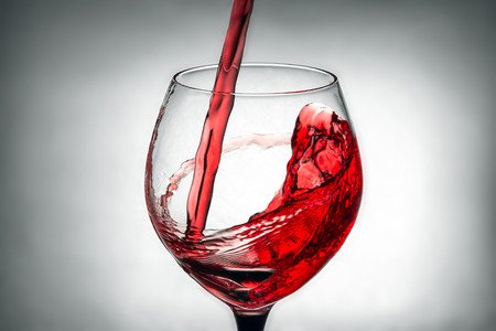 red wine pouring splash into glassの写真素材