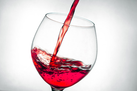 red wine pouring splash into glassの写真素材