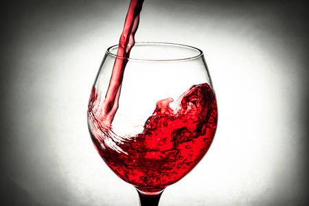 red wine in a glass splashの写真素材