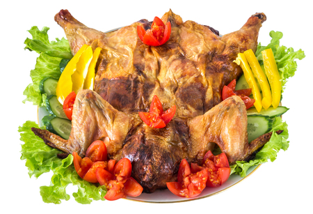 Whole stuffed and baked chicken adorned with vegetables and salad, isolated on white backgroundの写真素材