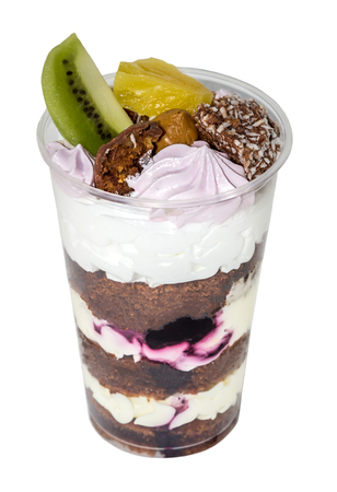 Trifle (cake in glass), chocolate biscuit cakes with cream cheese and blueberry jam, decorated with meringue, fruit (kiwi and pineapple) and candy, isolated on white backgroundの写真素材