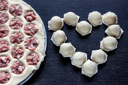 meat dumplings in the form of heart on dark wooden tableの写真素材