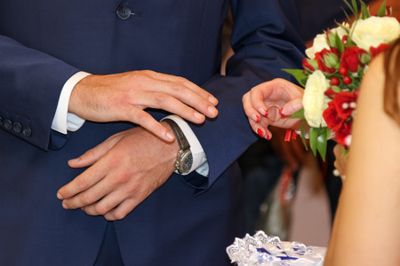 Exchange of wedding  rings.  Bride places the ring on the groom's hand.の写真素材